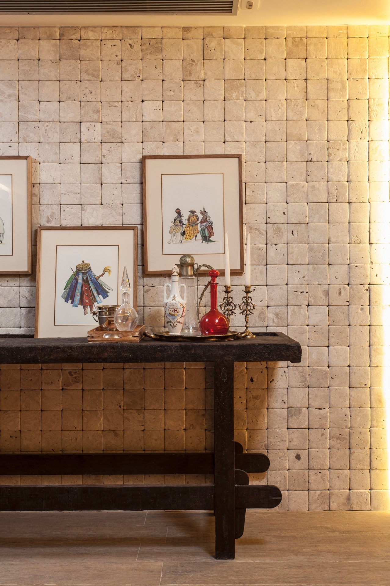 Na Copa e Cozinha, assinadas por Aiac Sacramento Caldas, uma das paredes ganha textura através do revestimento cimentício quadriculado que aparenta juntas secas. Nos quadros sobre o aparador, orixás estão representados. Dividida em duas mostras, a 19ª Casa Cor Bahia segue até dia 03 de novembro de 2013 nos estacionamentos do Shopping Iguatemi, em Salvador, e do Boulevard Shopping, em Feira de Santana - Xico Diniz/ Divulgação