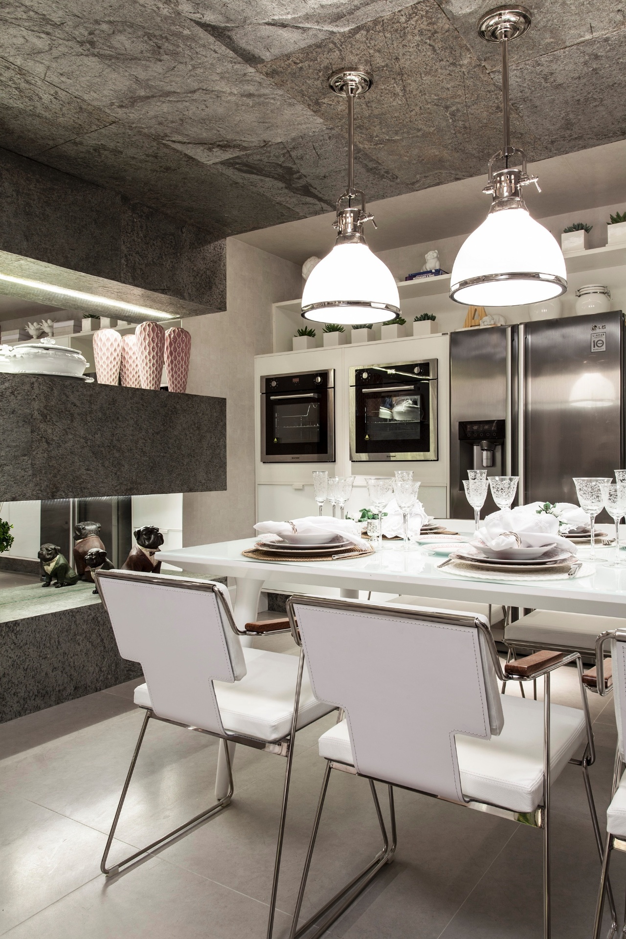 A Copa-Cozinha, assinada por Adelia Estevez, tem decoração com base cinza, combinada a pontos de rosa claro. O espaço ganha textura pelo rebaixo revestido de lâmina de pedra flexível (Carpaccio Di Pietra), onde estão instalados os pendentes. As lâminas também podem ser vistas nas prateleiras com fundo espelhado. Dividida em duas mostras, a 19ª Casa Cor Bahia segue até dia 03 de novembro de 2013 nos estacionamentos do Shopping Iguatemi, em Salvador, e do Boulevard Shopping, em Feira de Santana - Xico Diniz/ Divulgação