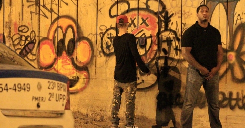 5.nov.2013 - Escoltado por segurança, Justin Bieber grafita muro do bairro de São Conrado, no Rio de Janeiro, durante a madrugada. O cantor e sua equipe foram para o local por volta das 3h. De acordo com a agência de fotografias AgNews, os fotógrafos presentes no local foram agredidos pelos seguranças de Bieber e a polícia chegou a ser chamada. O astro teen ficou grafitando por cerca de três horas e atendeu a fãs