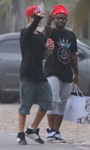 5.nov.2013 - Justin Bieber e sua equipe mostram o dedo do meio para paparazzi ao ver que estão sendo fotografados andando pela orla da praia da Barra da Tijuca