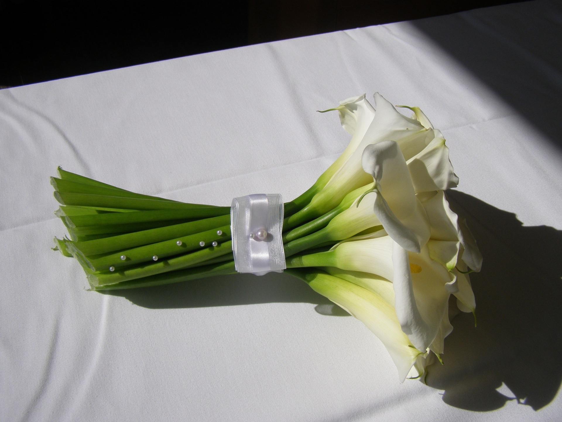 Buquê de copo-de-leite com haste envolta por fita branca e aplicações de pérolas ao longo das hastes - Divulgaçãp/Flor & Forma