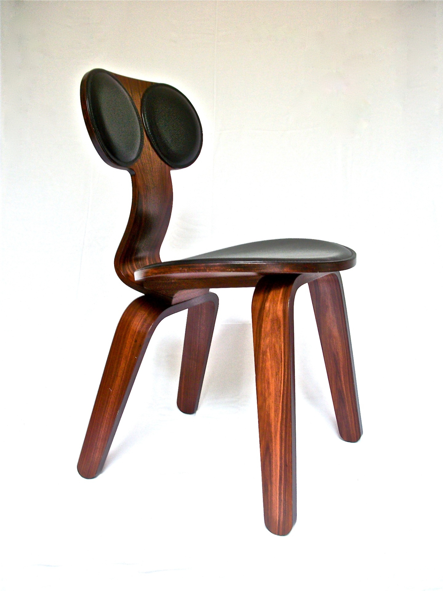 A cadeira  da linha Concha, criada pela Useche, é feita de madeira multilaminada e couro e mede 79 cm x 45 cm x 50 cm - Divulgação