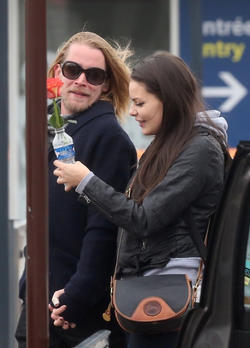 22.nov.2013 - O ator Macaulay Culkin recepciona a namorada em aeroporto de Paris com uma rosa colocada em uma garrafa plástica