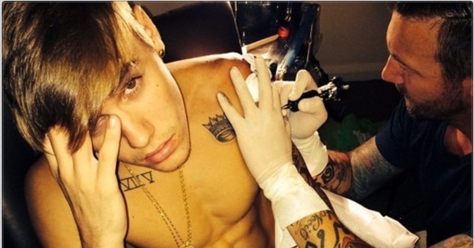 30.nov.2013 - Justin Bieber faz tatuagem nova. Na tarde deste sábado (30), o astro canadense compartilhou uma foto do momento em que ele aparece sendo tatuado em seu Instagram. No clique, o cantor aparece sem camisa com cara de dor. As fãs do cantor ficaram curiosas para saber qual o que Justin tatuou
