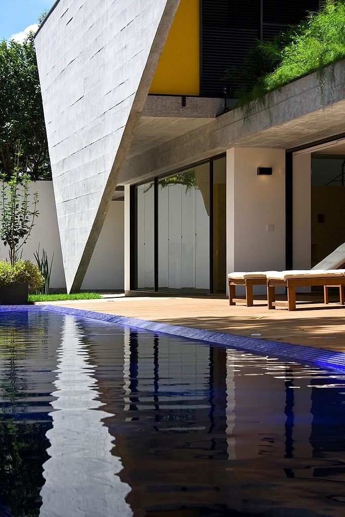 O grande destaque da Casa G+A, que tem projeto original dos arquitetos Carlos Lemos e Eduardo Corona e reforma assinada pelo escritório Stuchi&Leite, é a empena de concreto em formato triangular, cujo apoio no solo está reduzido a um único ponto. Além da beleza e originalidade, a estrutura funciona como superfície protetora contra a insolação direta na sala de estar, no térreo e nos dormitórios, no pavimento superior - Ana Mello/ UOL