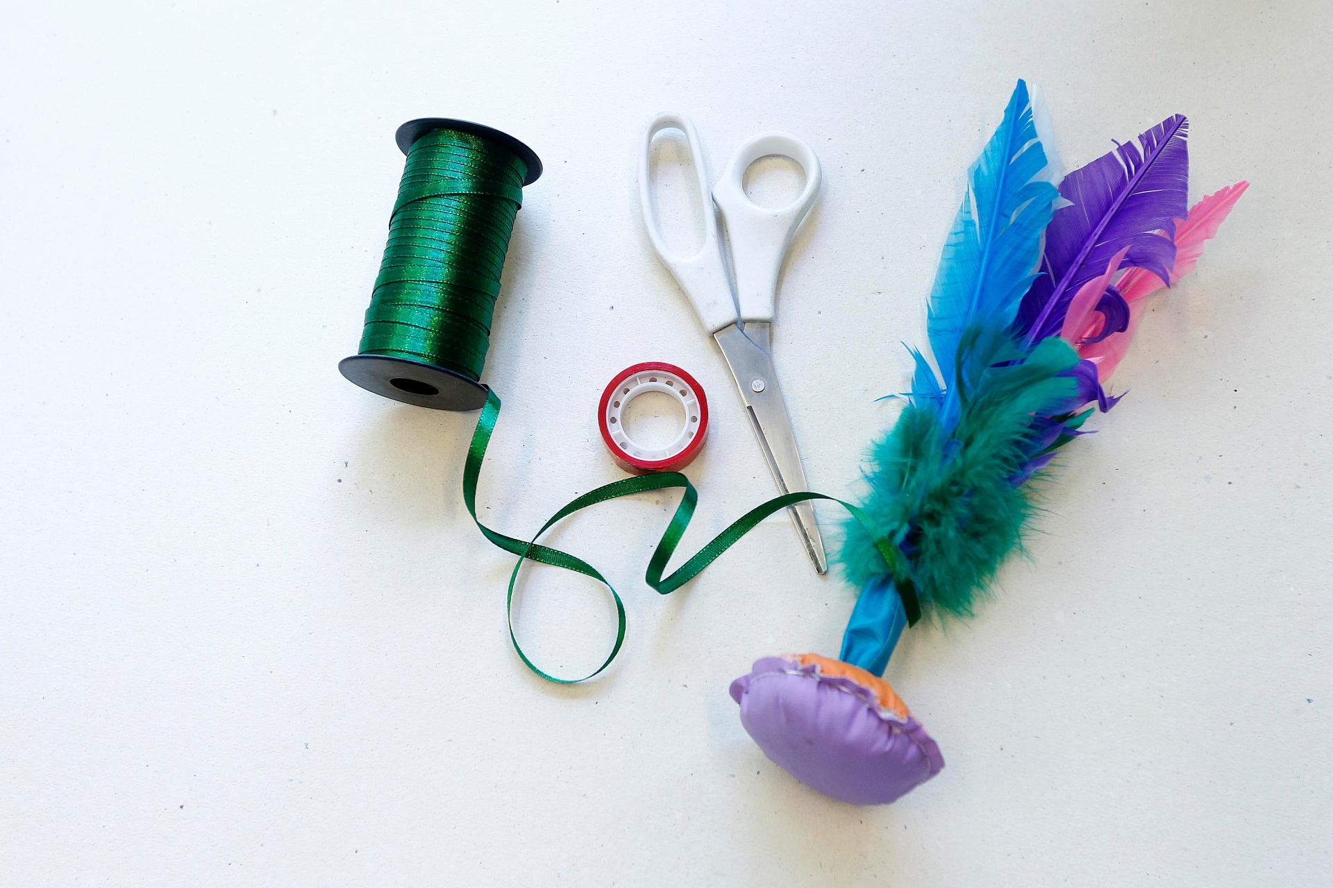 Em alguns casos, você precisará usar fita adesiva para conseguir pendurar o brinquedo na árvore de Natal. Para isso, use fita de cetim, tesoura, fita adesiva e um brinquedo que não tenha passem para a fita nem uma extremidade para amarrá-la. Dessa vez, Janaina usou uma peteca para exemplificar - Reinaldo Canato/UOL