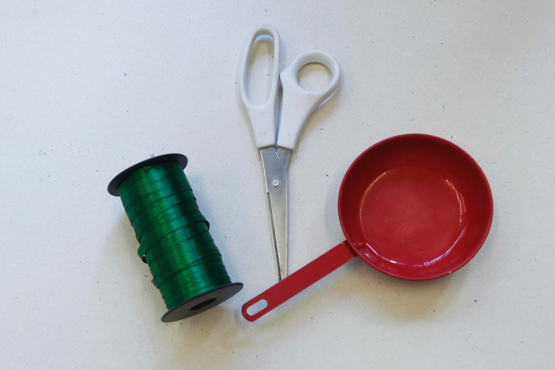 Para pendurar aqueles brinquedos que já têm algum furo ou passagem para a fita, você vai precisar de: fita de cetim, tesoura e o brinquedo, nesse caso, uma panelinha - Reinaldo Canato/UOL