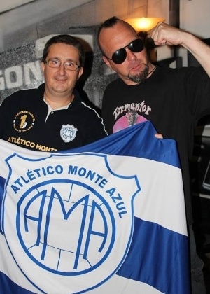 Vocalista Attila Csihar posa com um fã e a bandeira do clube de futebol Monte Azul durante a passagem pelo Brasil para show único em São Paulo, nesta quinta-feira (5)