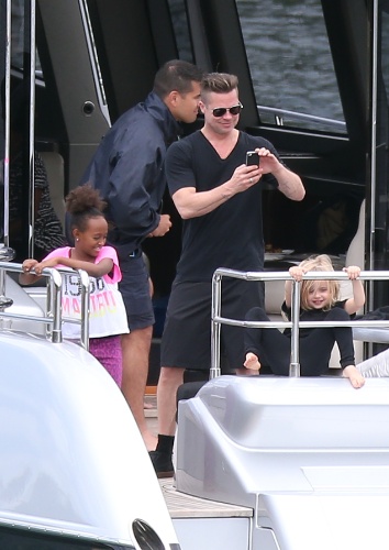3.dez.2013 - Ao lado das filhas Zahara e Vivienne, Brad Pitt fotografa o filho Knox fazendo stand up paddle em Sydney, na Australia