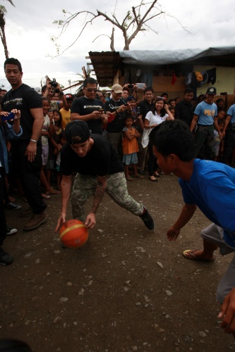 10.dez.2013 - O cantor Justin Bieber joga basquete com alunos sobreviventes do tufão Haiyan em escola de Tacloban, nas Filipinas