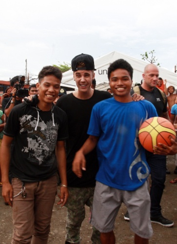 10.dez.2013 - O cantor Justin Bieber joga basquete com alunos sobreviventes do tufão Haiyan em escola de Tacloban, nas Filipinas