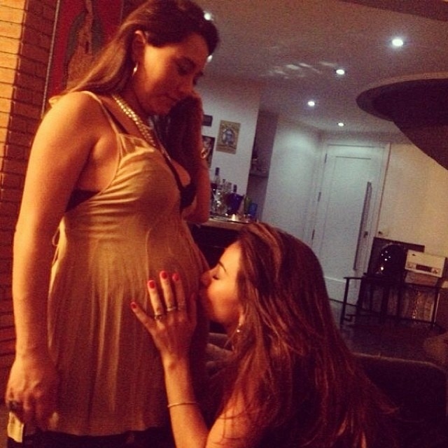 24.dez.2013 - Sabrina Sato beija a barriga da irmã Karina
