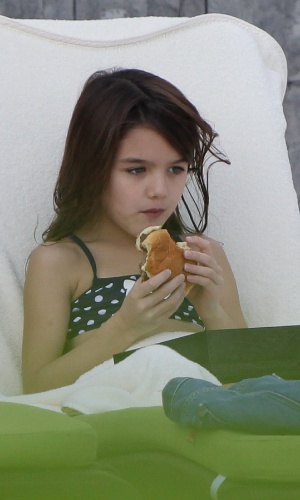 30.dez.2013 - Depois de brincar, Suri come um hambúrguer em piscina em Miami