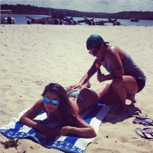 1.jan.2014 - Na praia, Thammy Miranda passa protetor solar no bumbum da nova namorada