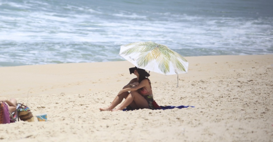 10.jan.2014 - Grávida, Alinne Moraes esconde a barriga em dia de praia