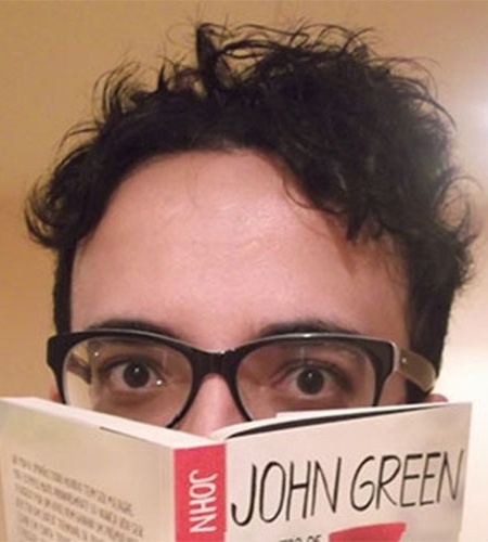 Alisson posa com o livro "Cidades de Papel", de John Green, no confinamento