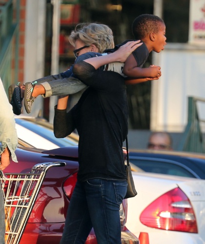 22.jan.2014 - A atriz Charlize Theron carrega o filho, Jackson, enquanto o namorado, Sean Penn, guarda as compras no carro