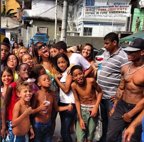 2013 - Ao lado dos moradores da favela da Rocinha no Rio de Janeiro, Sabrina Sato posa mostrando a língua