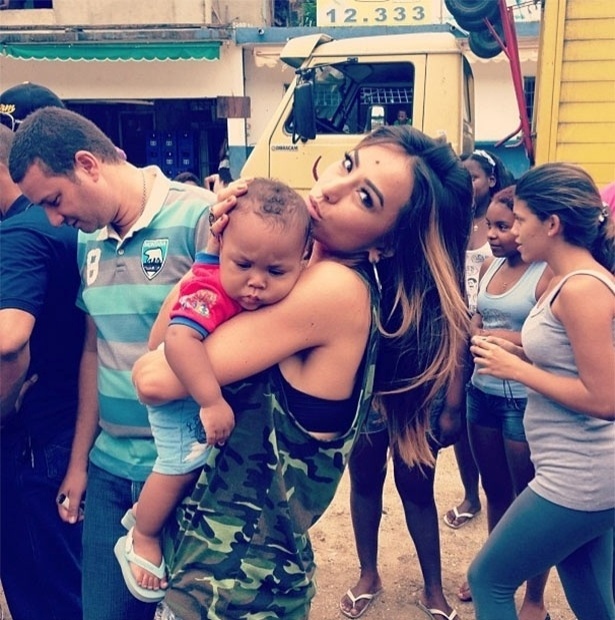 2013 - Na Rocinha, Sabrina Sato brinca com bebê da comunidade e faz "biquinho"