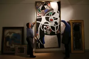 19.dez.2013 - Quadro "Mulheres e Flores", de Miró, parte da coleção de 85 telas cuja venda foi anulada, é manuseado em casa de leilão - Lefteris Pitarakis/AFP