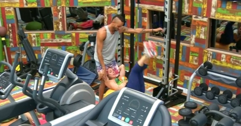 12.fev.2014 - Em posição inusitada, Valter Slim ajuda Aline a se exercitar na academia