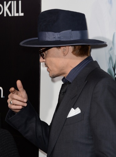 12.fev.2014 - Johnny Depp acompanha a namorada Amber Heard na première de "3 Days to Kill", em Hollywood. O ator deu um beijo carinhoso na atriz durante a passagem pelo tapete vermelho