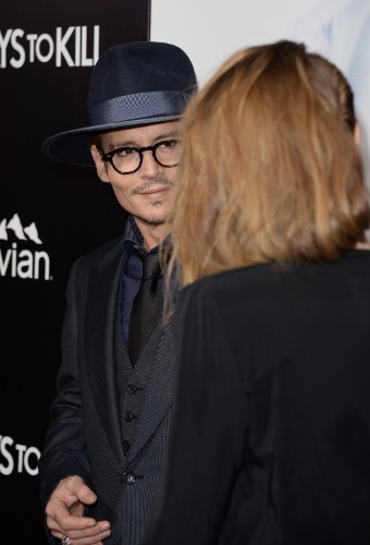 12.fev.2014 - Johnny Depp acompanha a namorada Amber Heard na première de "3 Days to Kill", em Hollywood. O ator deu um beijo carinhoso na atriz durante a passagem pelo tapete vermelho