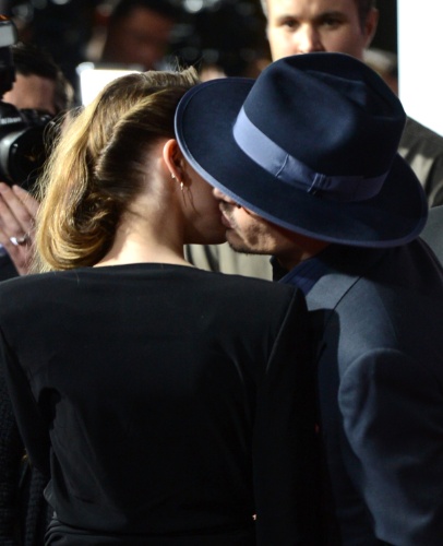 12.fev.2014 - Johnny Depp fala no ouvido de Amber Heard e dá um beijo carinhoso no rosto da namorada. Os dois, que estariam noivos, posam abraçados na première de "3 Days to Kill", em Hollywood