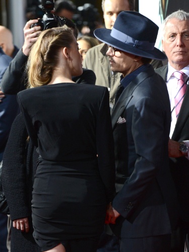 12.fev.2014 - Johnny Depp fala no ouvido de Amber Heard e dá um beijo carinhoso no rosto da namorada. Os dois, que estariam noivos, posam abraçados na première de "3 Days to Kill", em Hollywood
