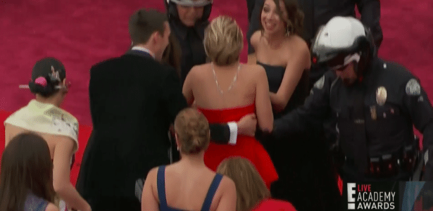 Jennifer Lawrence é apoiada por policial e amigo após tombo no tapete vermelho do Oscar 2014
