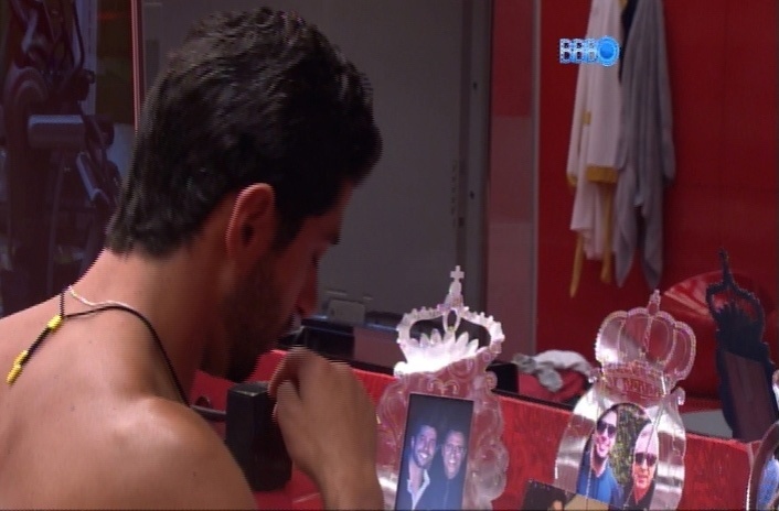 26.mar.2014 - Marcelo observa as fotos de seus familiares dispostas no quarto do líder e faz um sinal da cruz diante delas