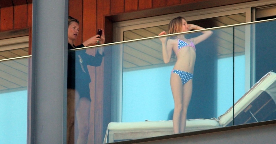 2.abr.2014 - Com o celular, Kate Moss tira foto da filha Lila Grace na sacada do hotel Fasano, no Rio de Janeiro. A top está no Brasil o baile de gala da amfAR, que acontece no dia 4