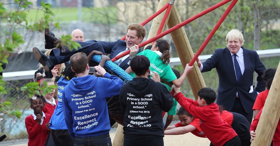 4.abr.2014 - Príncipe Harry brinca com crianças em balanço durante visita oficial ao Queen Elizabeth Olympic Park, em Londres