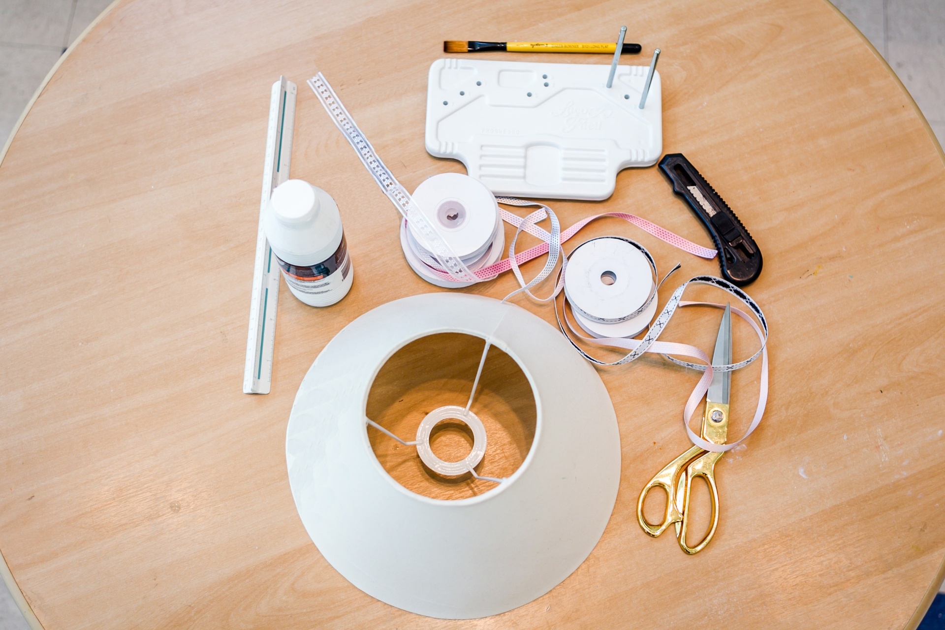 A outra opção de personalização para cúpula de abajur foi desenvolvida pela designer e cenógrafa Mon Liu (monliu@uol.com.br). Confira os materiais necessários: pincel, fazedor de laços, estilete, régua, cola branca, fitas, tesoura e cúpula - Leandro Moraes/UOL