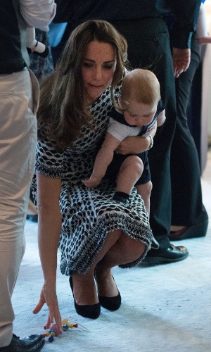 9.abr.2014 - Kate Middleton se agacha com o filho, Príncipe George, durante visita ao Palácio do Governo da Nova Zelândia, onde ela e o Príncipe William se reuniram com um grupo de pais e uma ONG que promove cuidados para crianças. Essa é a primeira viagem oficial do herdeiro de oito meses