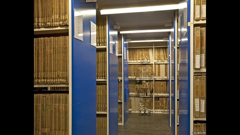 se camufla em meio às paisagens que deseja retratar, desde prateleiras de supermercado a estantes de biblioteca - ©Liu Bolin/Scream Gallery