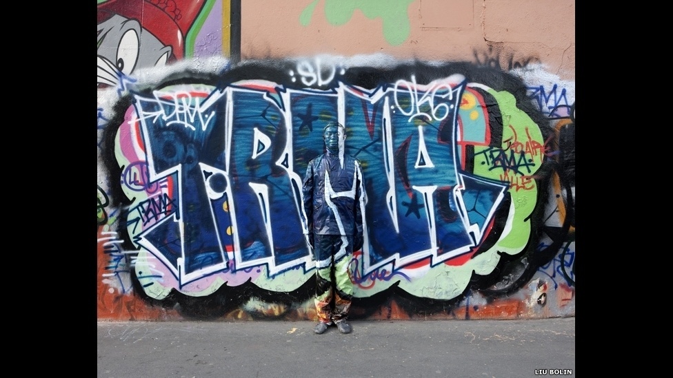 se camufla em meio às paisagens que deseja retratar, desde prateleiras de supermercado a estantes de biblioteca - ©Liu Bolin/Scream Gallery