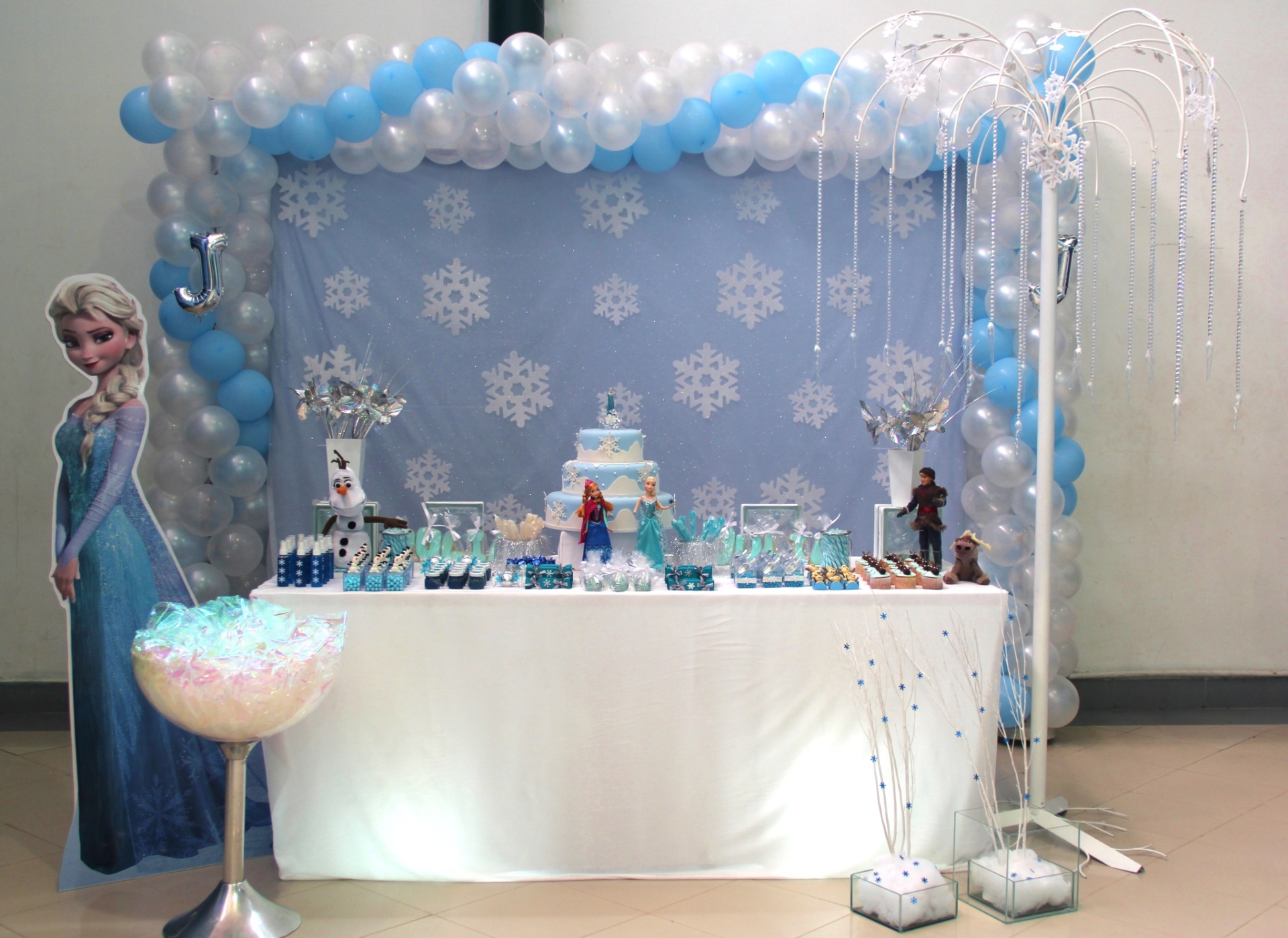 Na decoração em estilo clean, feita por Adriana Somma (www.metafestas.com.br), o tema era a animação "Frozen". As cores branco e azul predominam, aparecem nas bexigas, nos tecidos e nos detalhes da mesa. No chão, dois arranjos de galhos secos pintados de branco, com uma base feita em espuma, imitando flocos de neve, e uma estrutura de ferro com pingentes de miçanga - Divulgação