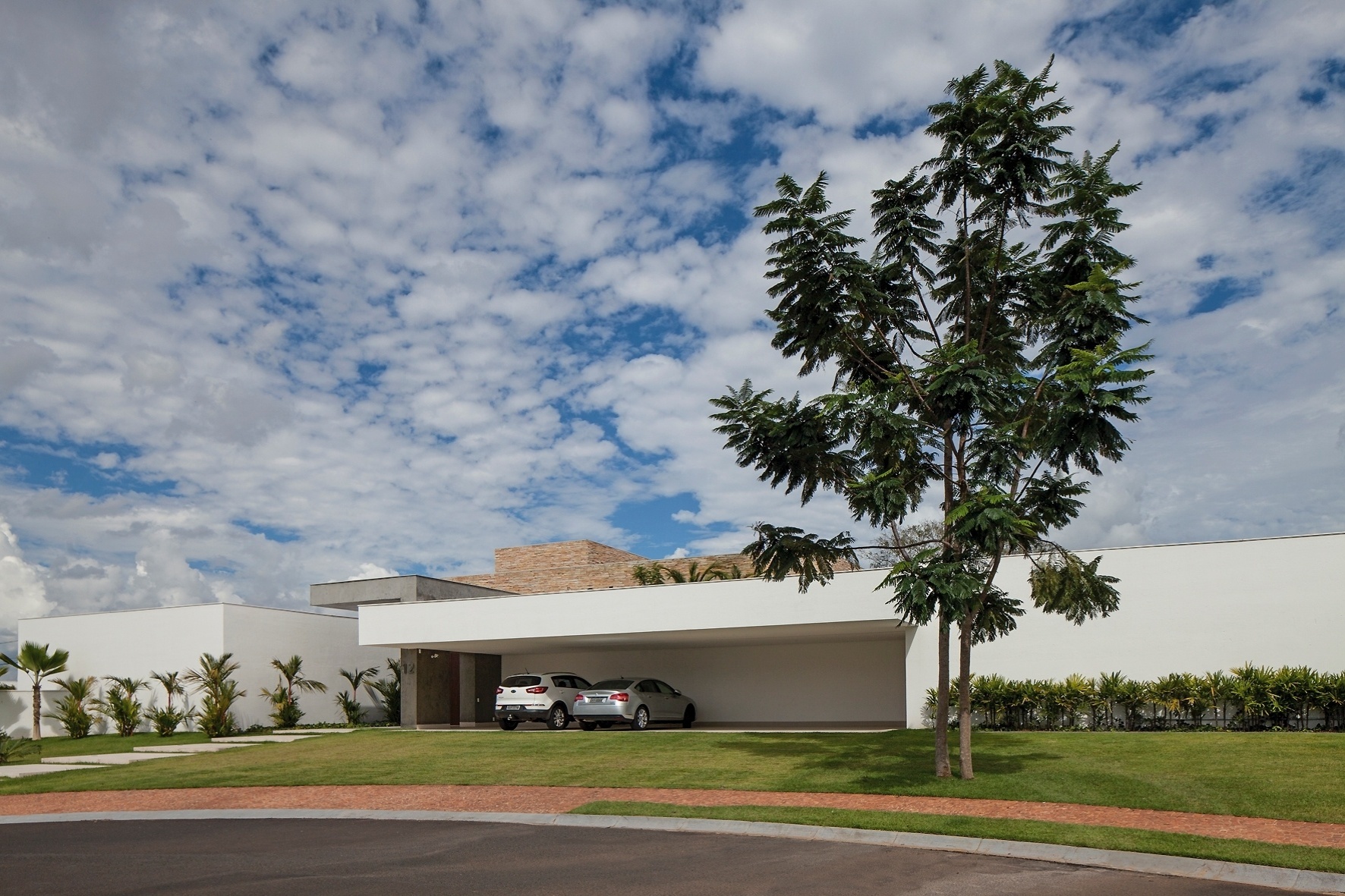 A fachada principal é marcada pela garagem com vão livre de 15 m, capaz de abrigar cinco automóveis. Um pórtico em concreto aparente destaca o hall de entrada e se estende até o corpo principal da residência - Leonardo Finotti/UOL