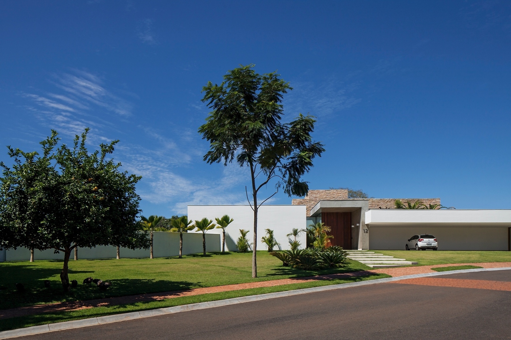 A fachada principal é marcada pela garagem com vão livre de 15 m, capaz de abrigar cinco automóveis. Um pórtico em concreto aparente destaca o hall de entrada e se estende até o corpo principal da residência - Leonardo Finotti/UOL