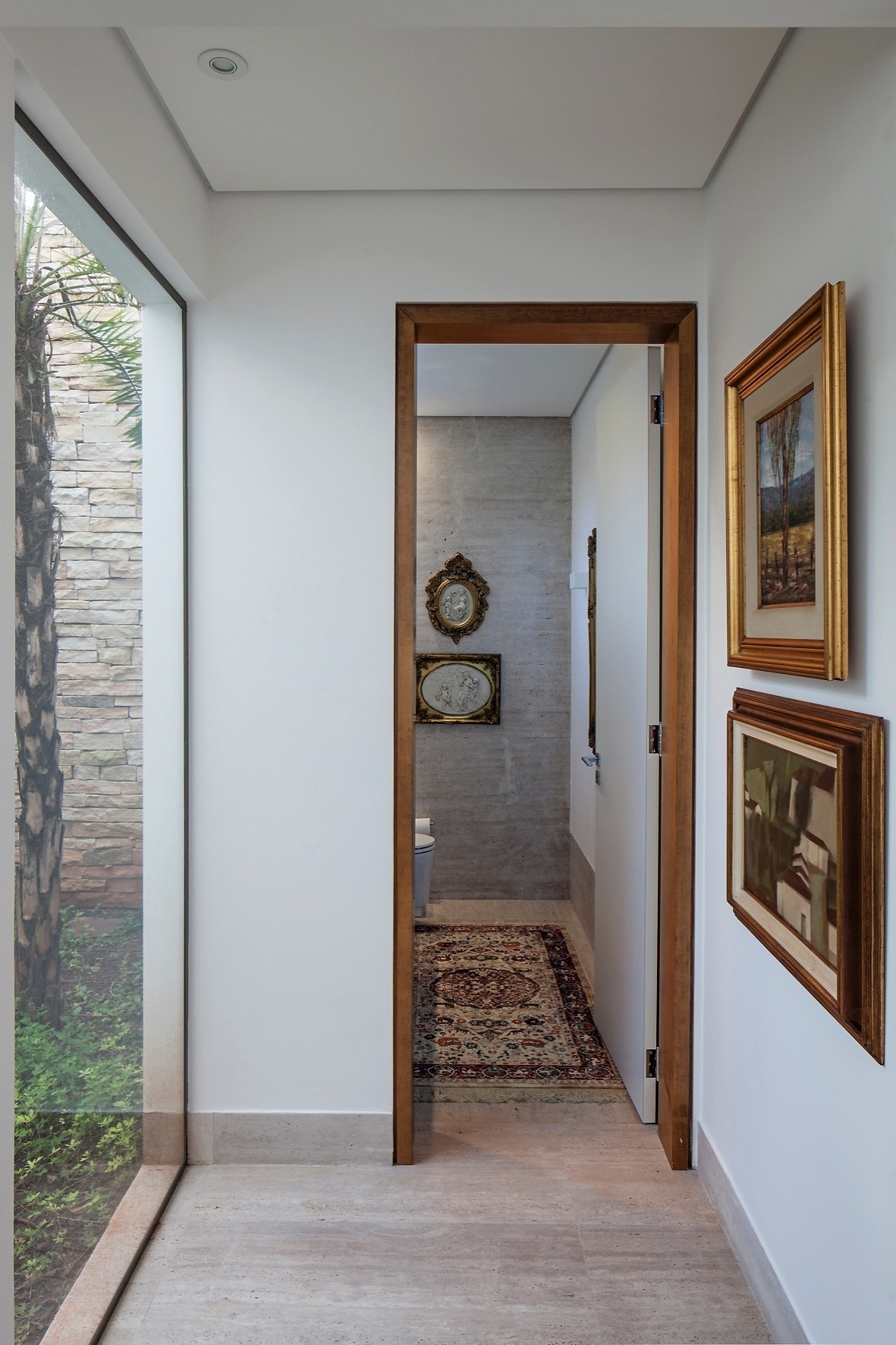 Com piso em mármore travertino, o corredor de acesso ao lavabo tem uma das laterais voltadas para o exterior. O fechamento em vidro permite a entrada de luz natural. O projeto da TB House é do escritório Aguirre Arquitetura - Leonardo Finotti/UOL