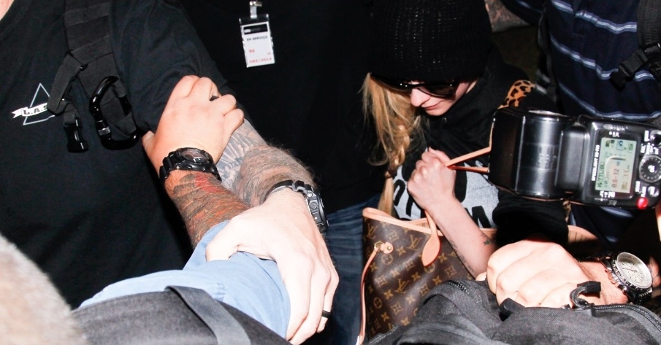 28.abr.2014- Seguranças cercam Avril Lavigne durante desembarque em São Paulo