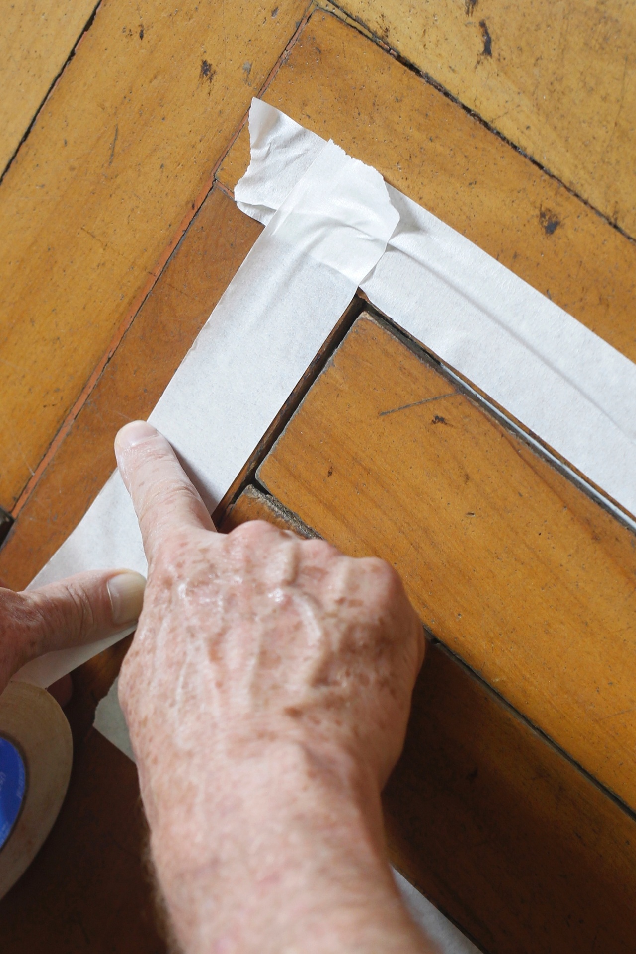 Após colar os tacos soltos, isole as bordas dos mesmos com fita crepe antes de iniciar a calafetação. Essa etapa consiste em tapar as fendas entre os tacos com a massa acrílica para madeira que pode ser encontrada em lojas de material de construção e reforma - Reinaldo Canato/UOL