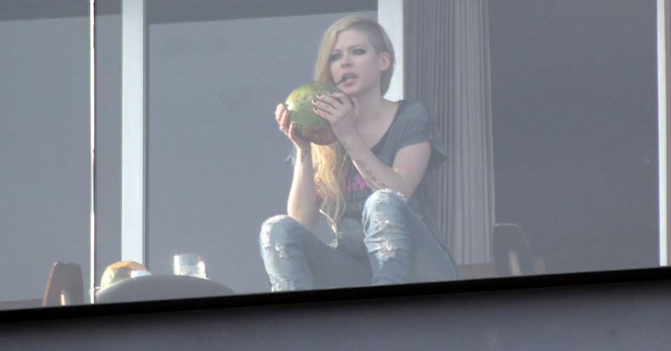 2.mai.2014 - Avril Lavigne apareceu bebendo água de coco na sacada do hotel onde está hospedada, no Arpoador, zona sul do Rio de Janeiro