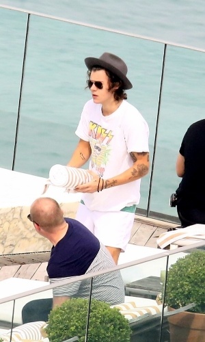 7.mai.2014 - De chapéu, camiseta da banda Kiss e óculos escuros, Harry Styles, do One Direction, é fotografado à beira da piscina do hotel Fasano, no Rio