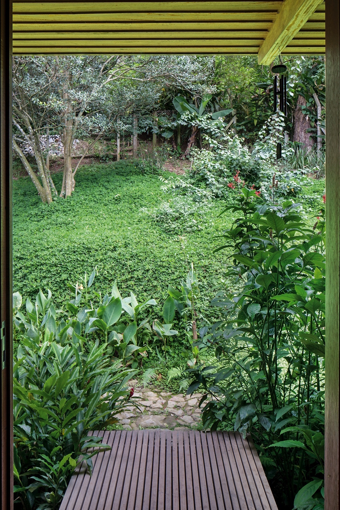 Uma pequena passarela de acesso liga a casa ao terreno no nível do ambiente de estar, e é a entrada principal da construção. O projeto da Casa Vila Taguaí, localizada em Carapicuíba (SP), tem assinatura da arquiteta Cristina Xavier e do engenheiro Hélio Olga - Leonardo Finotti/UOL