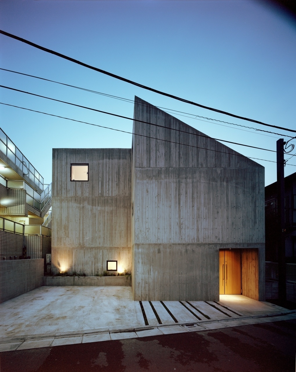 A fachada da Casa TN causa impacto: toda em concreto aparente, da rua, parece abrigar ambientes enclausurados e escuros. A arquitetura de geometria simples e reta, no entanto, esconde uma residência aconchegante em três pavimentos de uma senhora no andar térreo, mãe do morador que vive com sua esposa nos espaços do primeiro e do segundo andares. Por dentro, todos os ambientes são muito ricos em luz natural - Kai Nakamura/ Divulgação