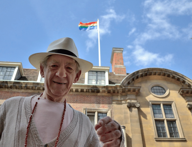 Ian McKellen posa em frente à sua antiga faculdade, St. Catherine, e mostra homenagem feita com bandeira do arco-íris