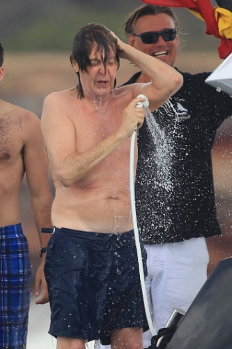 23.jun.2014 - Paul McCartney toma ducha com um chuveirinho após dar mergulho no mar em Ibiza, na Espanha, e direciona o jato para amigo. Segundo informações da agência Grosby Group, o cantor depois recebeu uma toalha vermelha de uma amiga para se secar