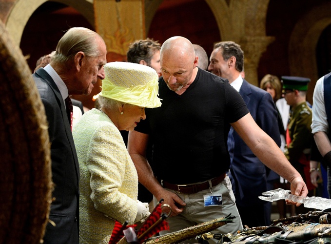 24.jun.2014 - A Rainha Elizabeth 2ª e o marido, o Príncipe Philip, olham acessórios e figurinos de "Game of Thrones" durante visita ao set de filmagens da série em Belfast, na Irlanda do Norte